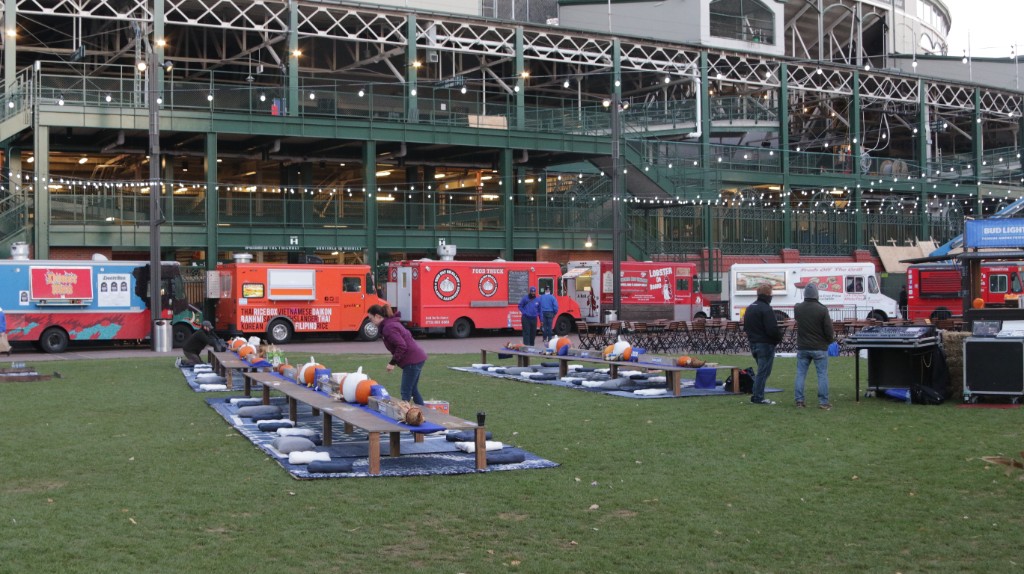 Guests at long outdoor tables with pumpkins and Bud Light decor under string lights at Gallagher Way