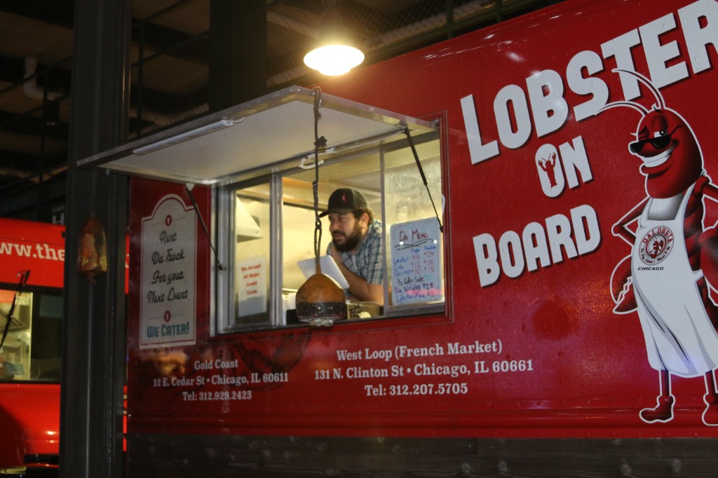 Oversized letter tiles on a lawn spelling Bud Light and Friendsgiving beside hay bales and a pumpkin