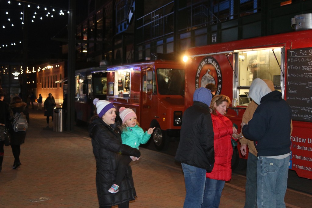White and orange pumpkins with Bud Light cans and purple fairy lights on a harvest table at night