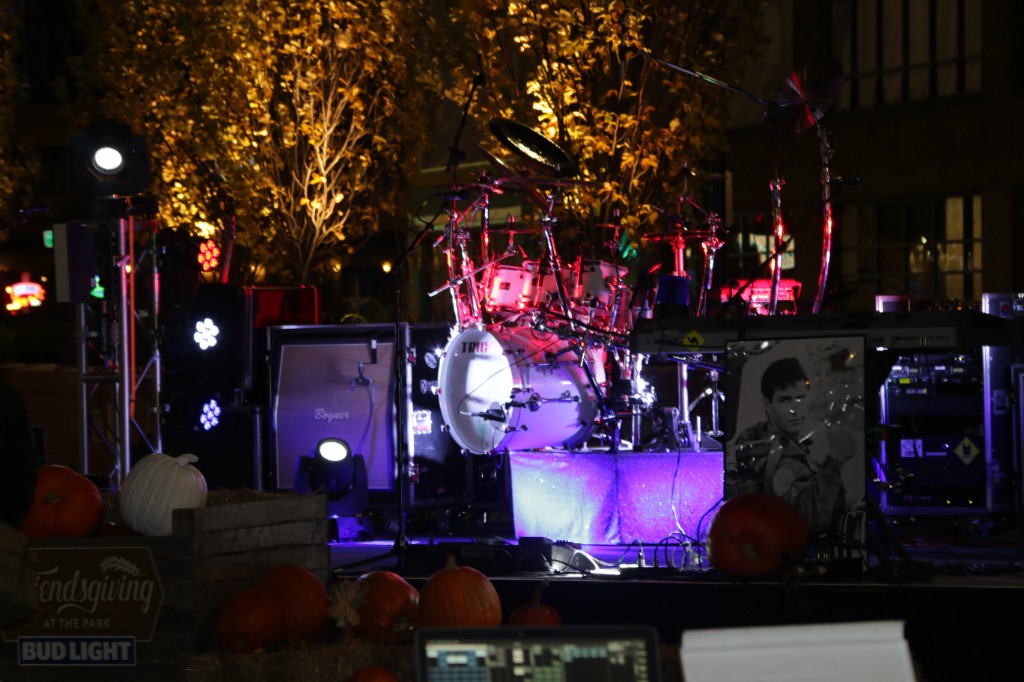 Live band on a purple-lit stage with a Bud Light Famous Among Friends banner and string lights overhead