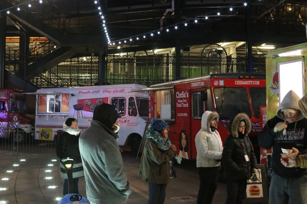 Four-piece band with guitars, bass, and drums lit by magenta spotlights at night