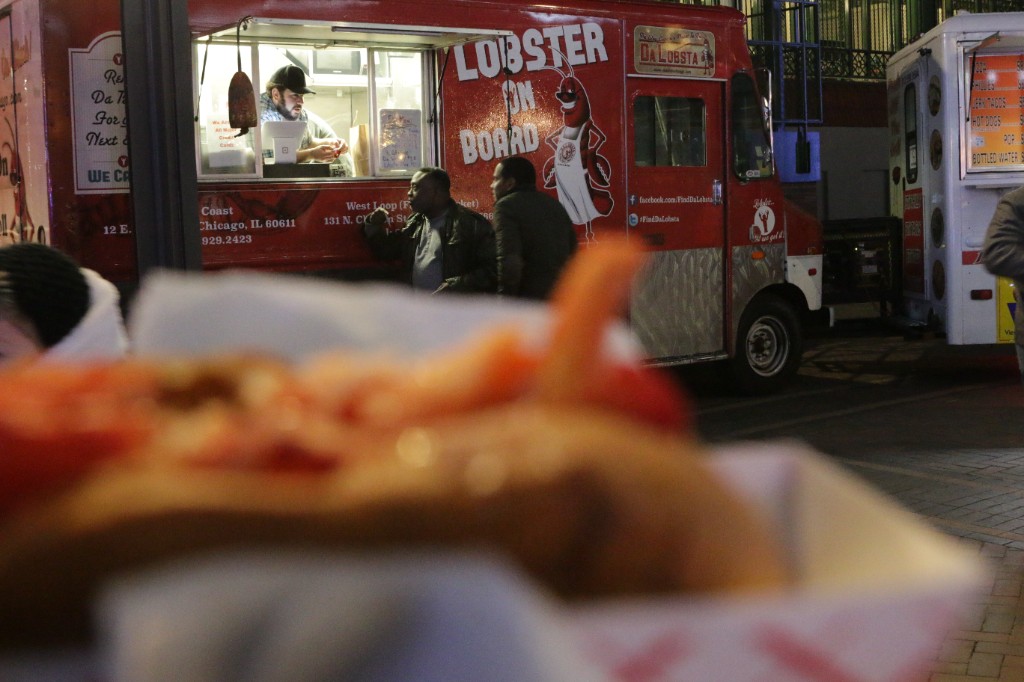 Chicago Food Truck Fest lineup on the video board above the illuminated Cubs Store at night
