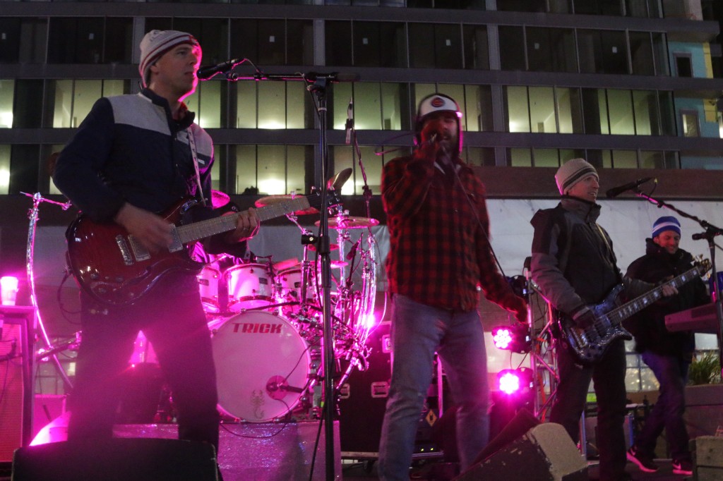 Pink and purple stage lights washing over performers and equipment at night