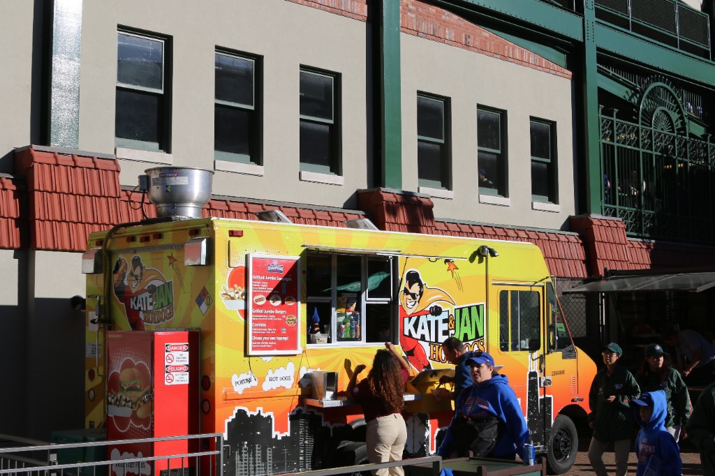 Guest holds a loaded hot dog in a paper tray outside the ballpark