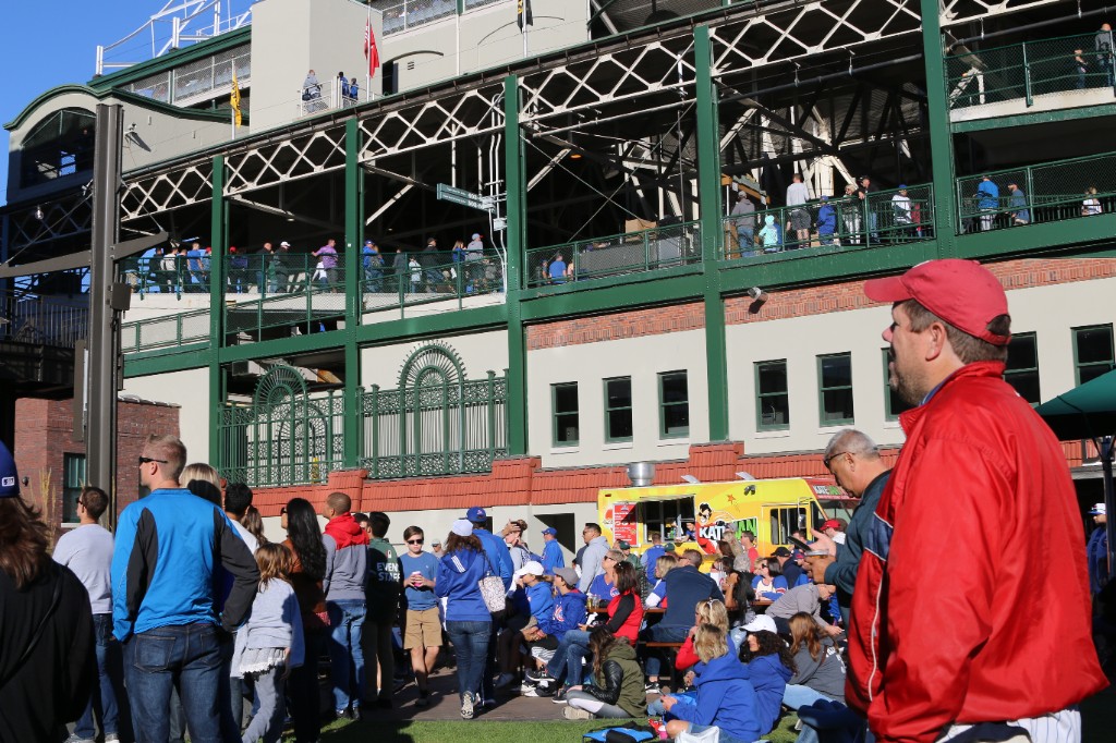Crowd outside Wrigley Field with a yellow food truck on a sunny game day