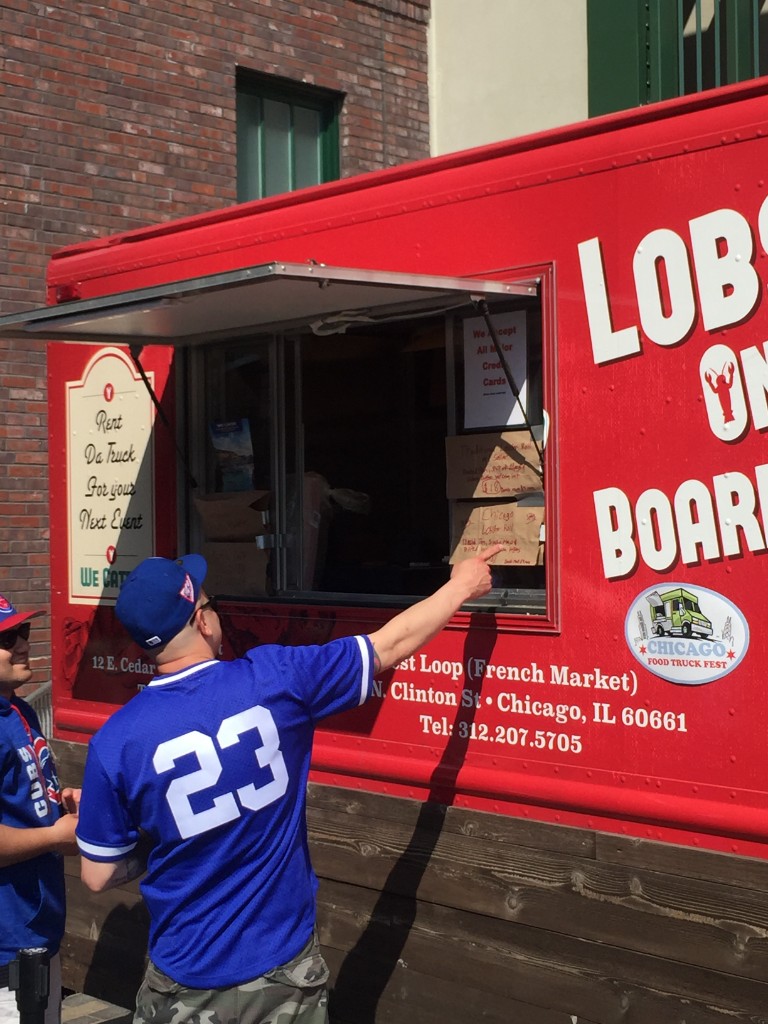 Fans in Cubs jerseys ordering at the Da Lobsta truck outside Wrigley Field